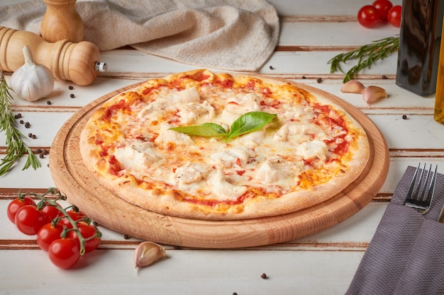 Pizza mit Scheiben, Sauce und Kräutern, Holzweiß