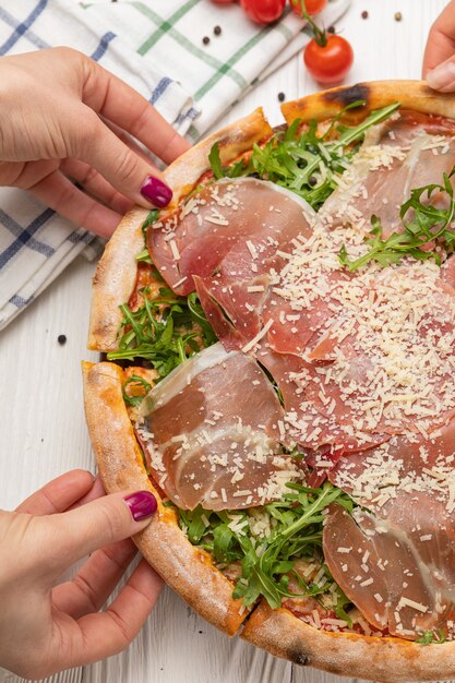 Pizza mit Schinken, Rucola, Tomaten und Parmesan