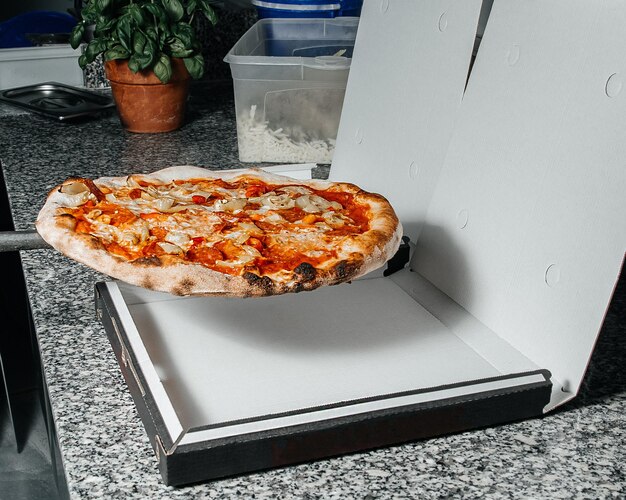 Pizza mit Schinken und Käse in einer Schachtel weiter für das Pizzeria-Lieferkonzept