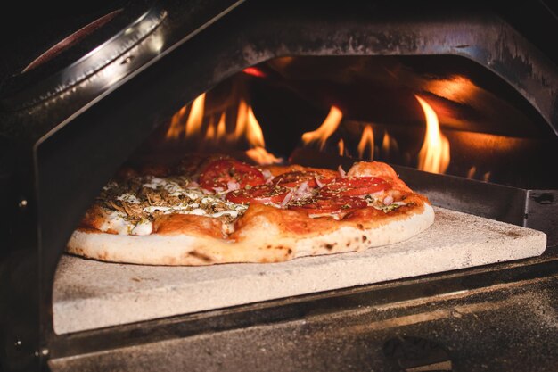 Pizza mit Schinken und Weißkäse, die in einem Elektroofen zubereitet wird