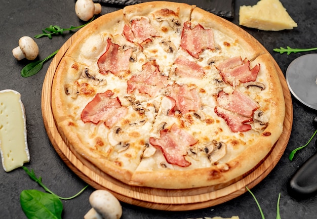 Pizza mit Speckpilzen und Käse auf Steingrund
