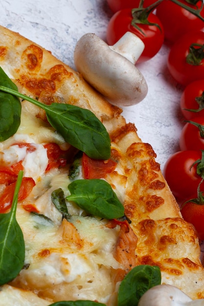 Pizza mit Spinat, Kirschtomaten und Gorgonzola-Käse auf einem hellen Hintergrund