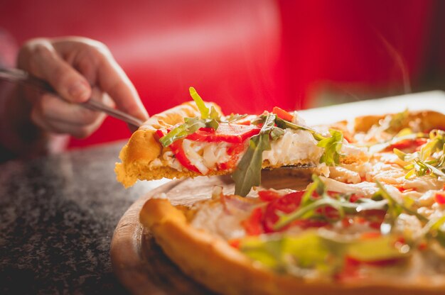 Pizza mit Tomaten auf einem Holzbrett.