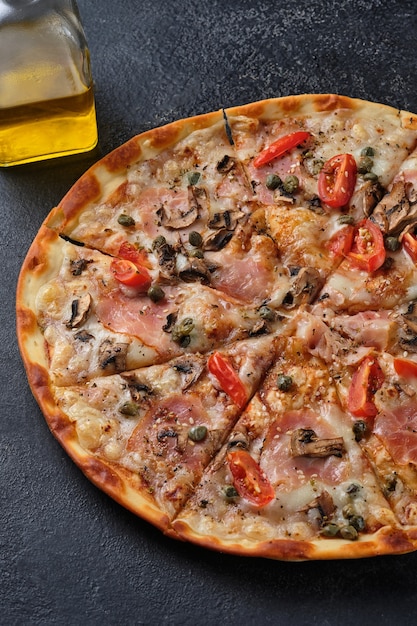 Pizza mit Tomaten Schinken Kapern Champignons Mozzarella Käse Gewürze Sesam Tomatensauce