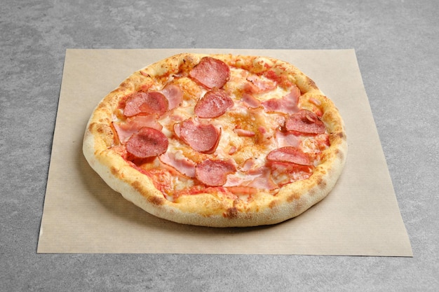 Pizza mit Wurst und Schweineschinken auf Pergamentpapier