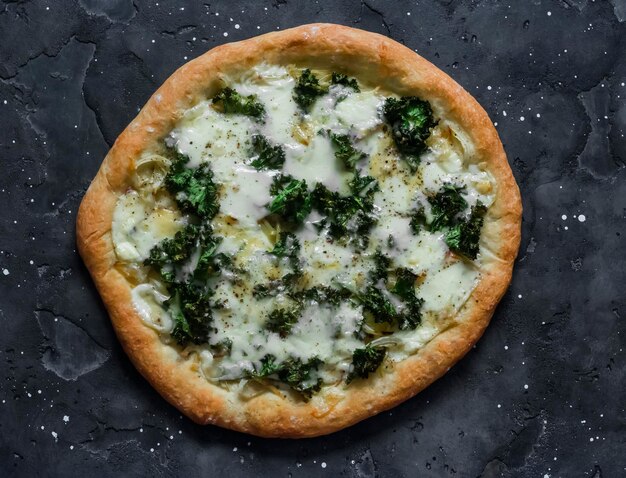 Pizza de mozzarella de kale de patata vegetariana en una vista superior de fondo oscuro