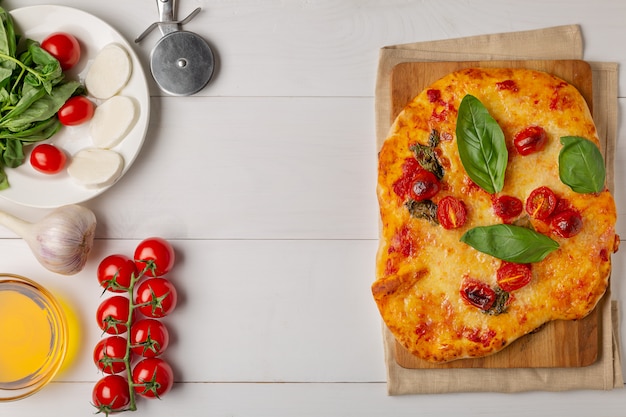 Pizza con mozzarella, tomates cherry a la mitad, especias y albahaca fresca