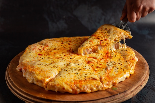 Pizza con mucho queso derretido sobre un fondo oscuro Pizza italiana