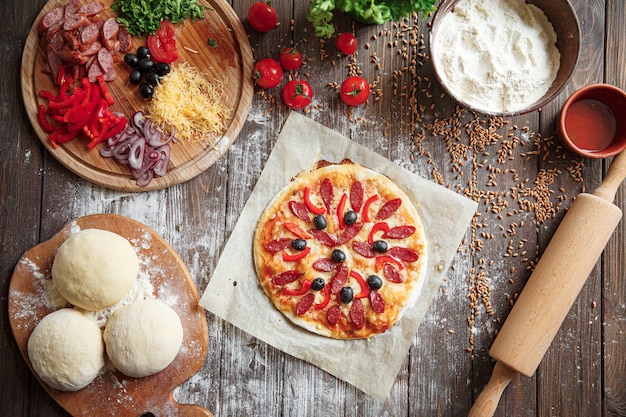 Pizza não cozida com ingredientes na mesa