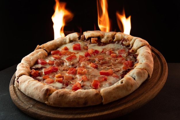 Pizza napalita com tomate em fundo escuro com fogo cozinhando pizza em fogo pizza com chamas