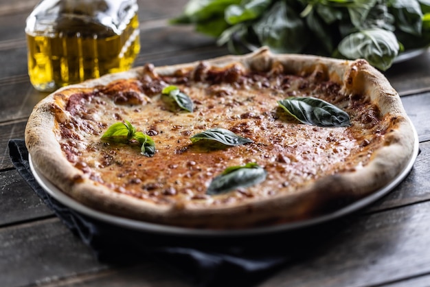 Pizza Napoli con salsa de tomate y albahaca fresca mozzarella y una jarra de aceite de oliva en el fondo