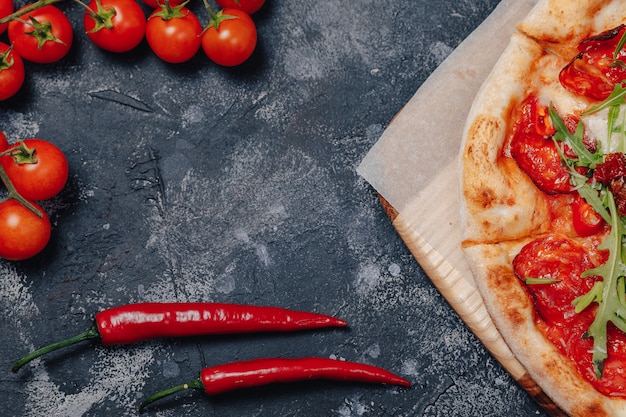 Pizza napolitana apetitosa picante a bordo con tomates cherry y chile, espacio libre para texto