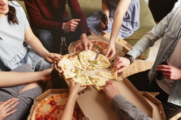 Foto pizza-party-gruppe von freunden, die sich unterhalten, pizza essen, süßes sodawasser trinken?