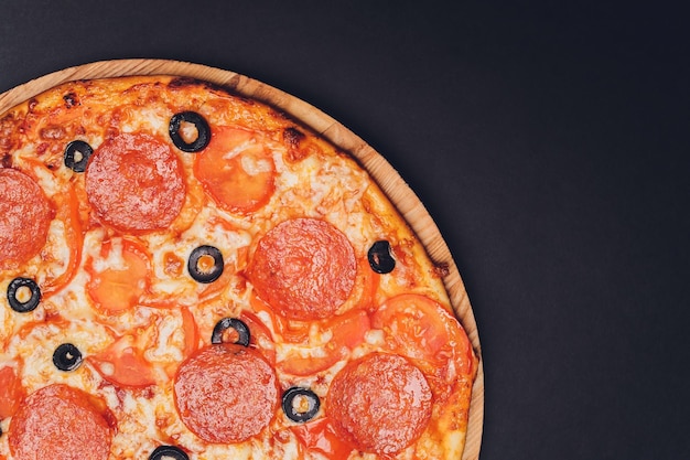 Pizza Peperoni Mozzarella Oregano auf schwarzem Hintergrund