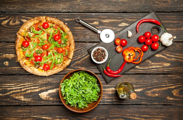 Pizza de pepperoni con ingredientes sobre fondo de madera