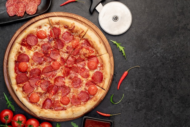 Pizza de pepperoni con ingredientes sobre fondo de piedra con espacio para copiar el texto