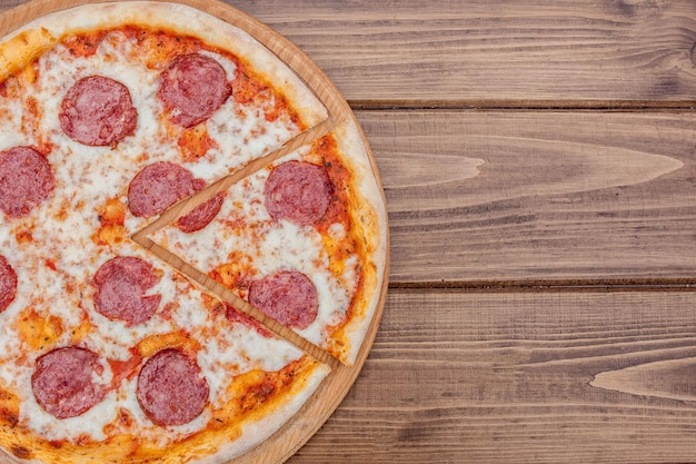 Foto pizza de pepperoni italiana con salami sobre fondo de madera oscura vista superior comida tradicional italiana comida callejera popular