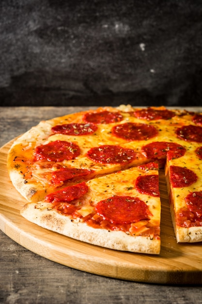 Pizza de pepperoni italiano caliente en la mesa de madera.