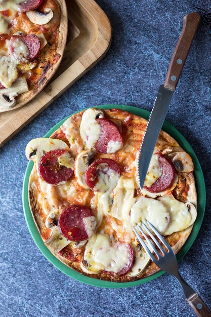 Foto pizza de pepperoni con queso mozzarella, champiñones blancos y sriracha