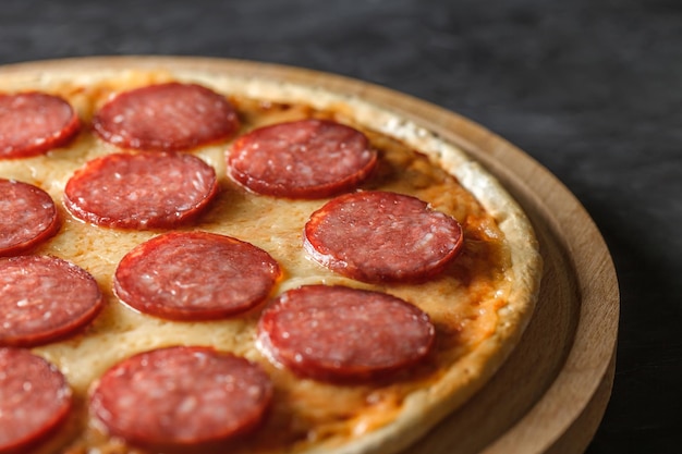 Pizza de pepperoni con salchicha en un soporte de madera redondo efecto bokeh de enfoque selectivo