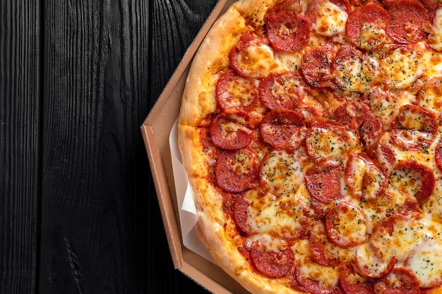 Pizza de pepperoni sobre tablero de madera negro oscuro