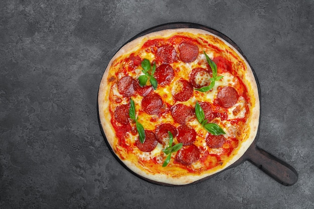 Pizza de pepperoni con tomates cherry, queso sobre fondo negro
