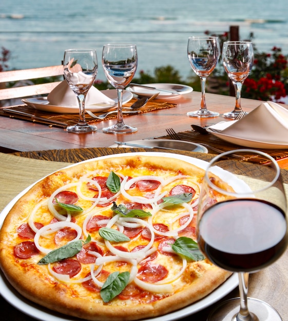 Pizza de pepperoni y vino tinto, pizzería en la playa