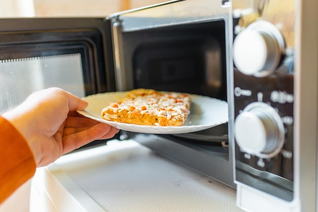 Pizza pequeña congelada sin cocer colocada en el microondas comida chatarra concepto de comida rápida vista lateral enfoque selectivo