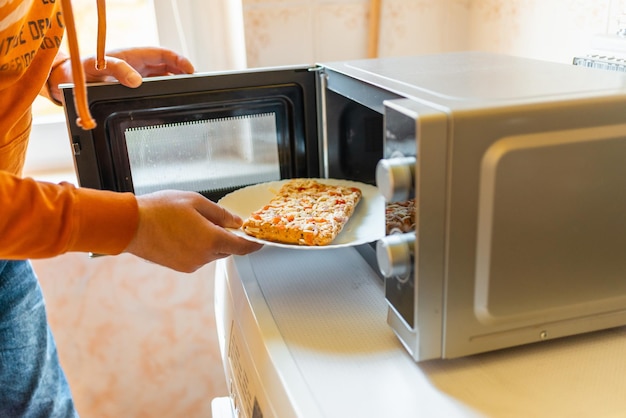 Pizza pequeña congelada sin cocer colocada en el microondas comida chatarra concepto de comida rápida vista lateral enfoque selectivo