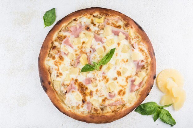 Foto pizza con piña y pollo, salsa césar, jamón, queso mozzarella sobre un fondo claro. vista superior con espacio para copiar el texto. comida italiana clásica.