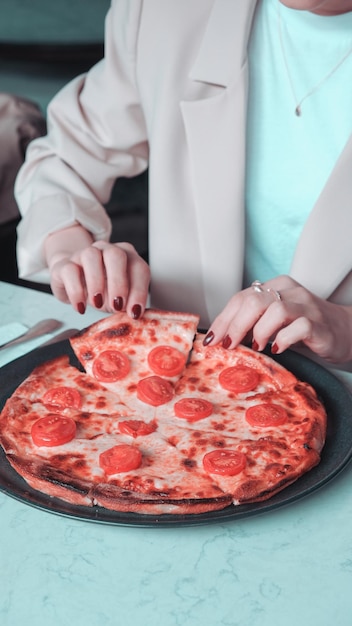 una pizza en un plato con una mujer cortando una rebanada de pizza