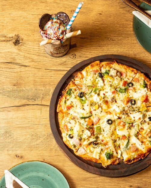 Una pizza en un plato con un sombrero de paja a un lado.