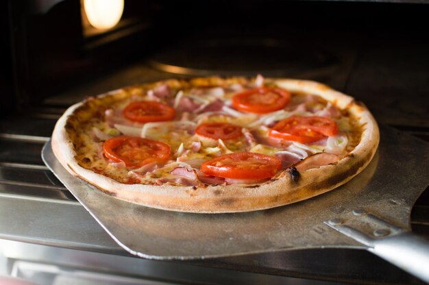 La pizza preparada se retira del horno Deliciosa pizza crujiente caliente