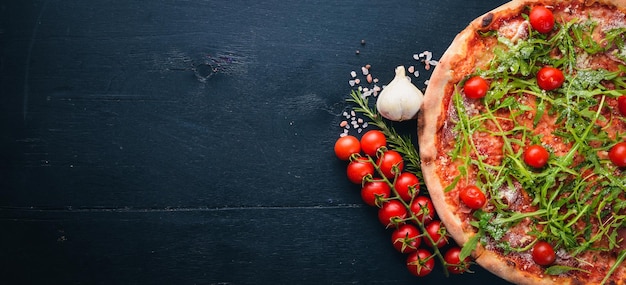 Pizza Primavera. Kirschtomaten, Rucola, Käse. Auf einem hölzernen Hintergrund. Ansicht von oben.