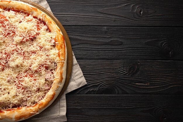 Pizza pronta para o forno em um fundo de madeira, lugar para texto, vista superior.