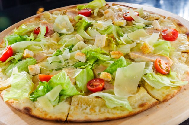 Pizza con prosciutto y rúcula en mesa de madera.