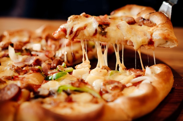 Pizza, queso y refrescos en una mesa de madera.