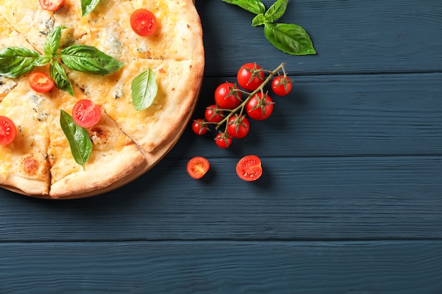 Pizza de queso con tomate y albahaca sobre fondo de madera