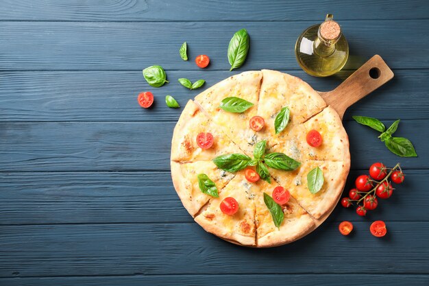 Pizza de queso, tomates y aceite de oliva sobre fondo de madera