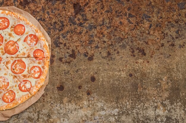 Foto pizza con queso y tomates con espacio de copia sobre un fondo de metal brutal inusual con óxido.