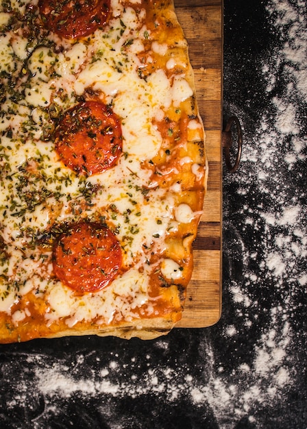 Pizza con queso y tomates sobre una superficie negra