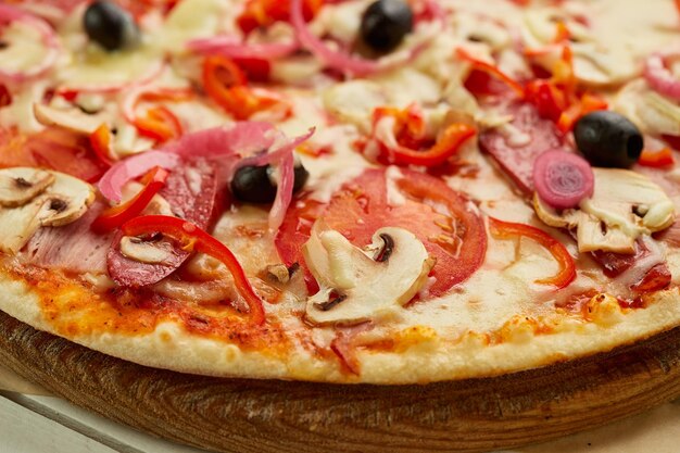 Pizza recém-assada com salsichas defumadas pimenta vermelha cogumelos cebola e azeitonas servidas em fundo de madeira com molho de tomate e ervas Conceito de entrega de comida Menu de restaurante