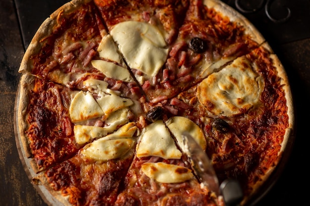 Pizza recién cocinada Vista superior Cortada en trozos Fondo oscuro Primer plano