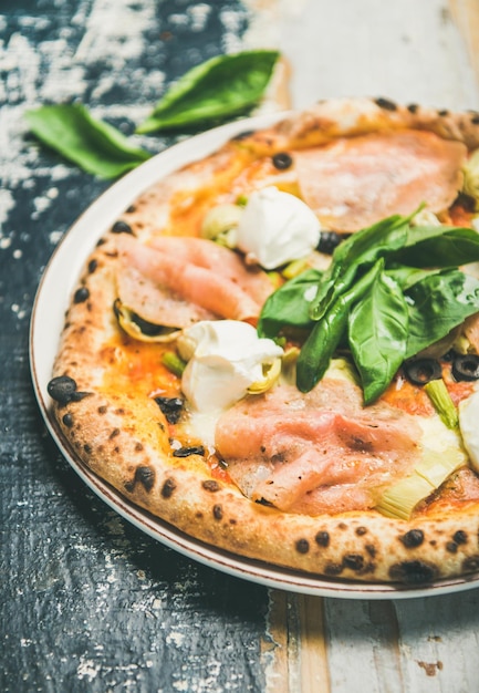 Pizza recién horneada con alcachofas de jamón y queso crema closeup