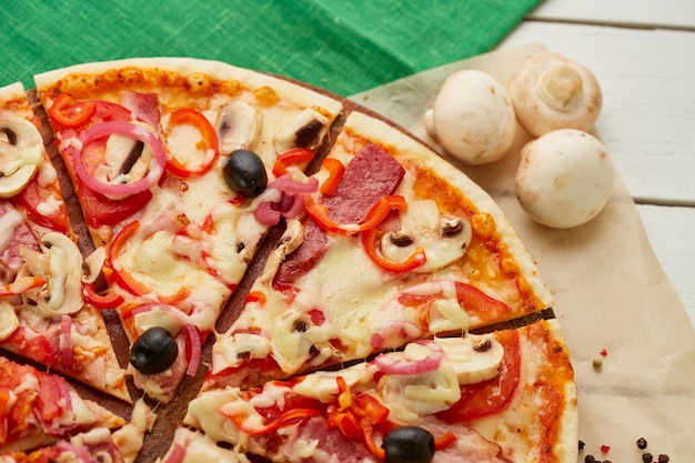 Pizza recién horneada con salchichas ahumadas pimiento rojo champiñones cebolla y aceitunas servidas sobre fondo de madera con salsa de tomate y hierbas Concepto de entrega de alimentos Menú del restaurante