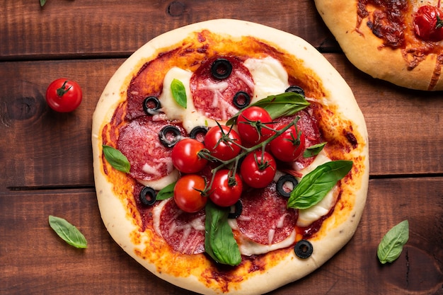 Pizza recién horneada con tomate y albahaca sobre una tabla de madera