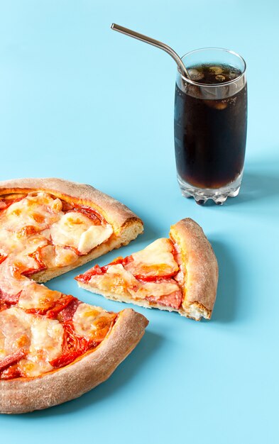 Pizza y refrescos con hielo sobre un fondo azul.