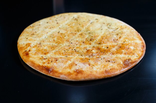 Pizza en rodajas sobre un fondo de piedra negra, vista superior. Focaccia recién horneada con queso