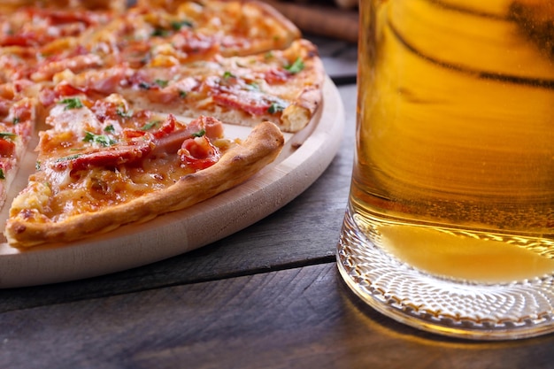 Pizza en rodajas y vaso de cerveza en la mesa de madera de cerca