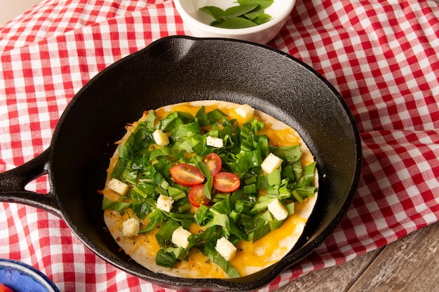 Pizza de rúcula con queso y tomates de cereza en una sartén de hierro fundido